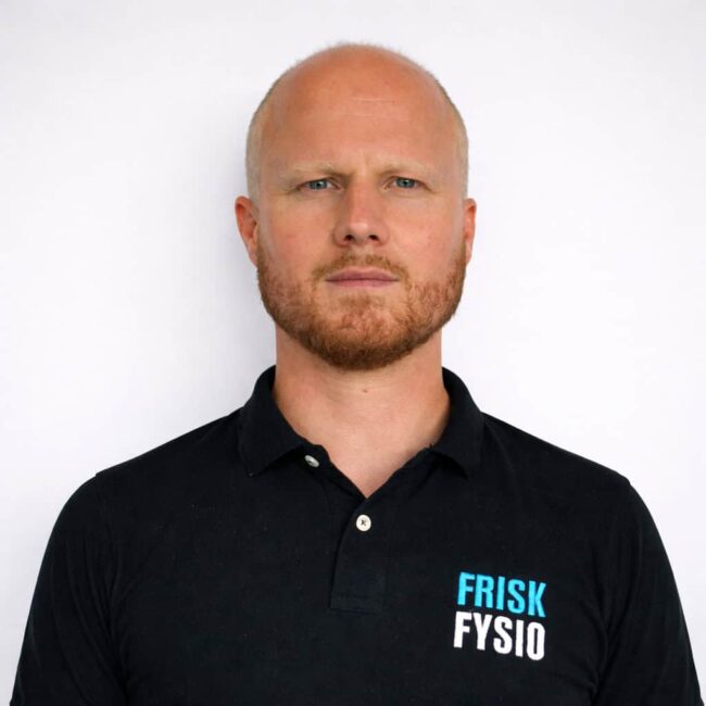 Man met korte blonde baard en een zwart polo met Frisk Fysio logo, professioneel en vriendelijk, klaar om te helpen met fysiotherapie en herstel.
