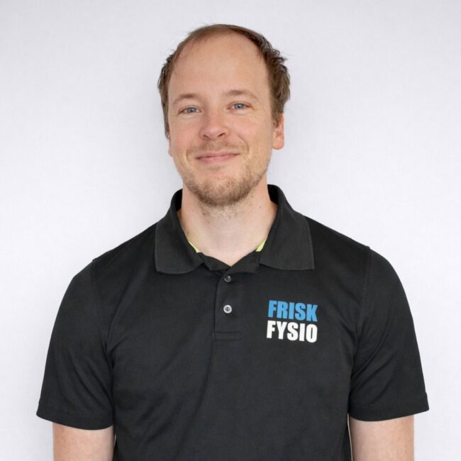 FriskFysio Erwin - Physiotherapist in the Netherlands Erwin, physiotherapist at FriskFysio, poses in black polo shirt with logo, smiling, on white background.
