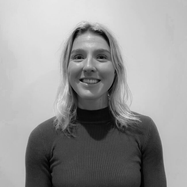 IMG_7856_jpg Faces of a smiling young woman in black and white, casual dress, indoors, friendly appearance, professional medical and physiotherapy environment, satisfied customer, health and wellness focus.