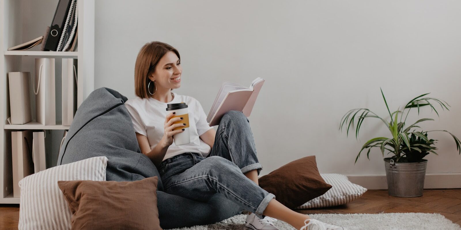 vrouw ontspant met een boek en een kop koffie om spierklachten te voorkomen