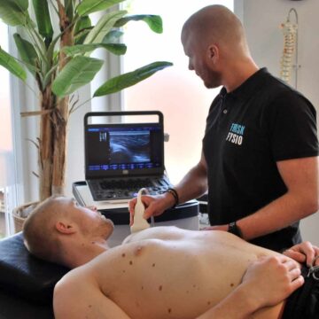 Ultrasone pijnbestrijding bij een mannelijke patiënt met een fysiotherapeut in een kliniek; sportfysiotherapie en revalidatie, medische behandeling, herstel van spierproblematiek.