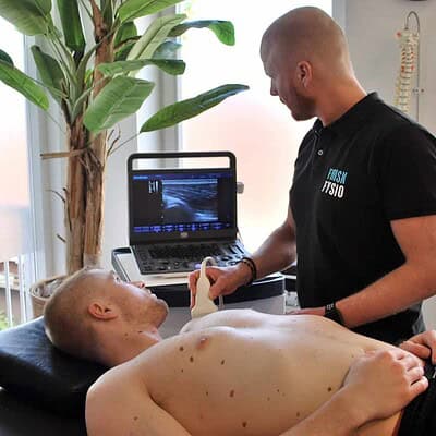 Ultrasone pijnbestrijding bij een mannelijke patiënt met een fysiotherapeut in een kliniek; sportfysiotherapie en revalidatie, medische behandeling, herstel van spierproblematiek.