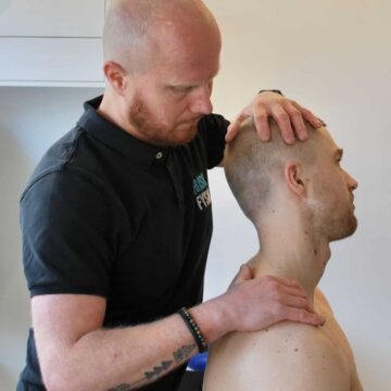 A physiotherapist examines the neck of a seated client