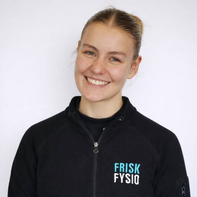 Kelsey glimlachend in sportkleding bij Frisk Fysio, klaar voor fysiotherapie of training.
