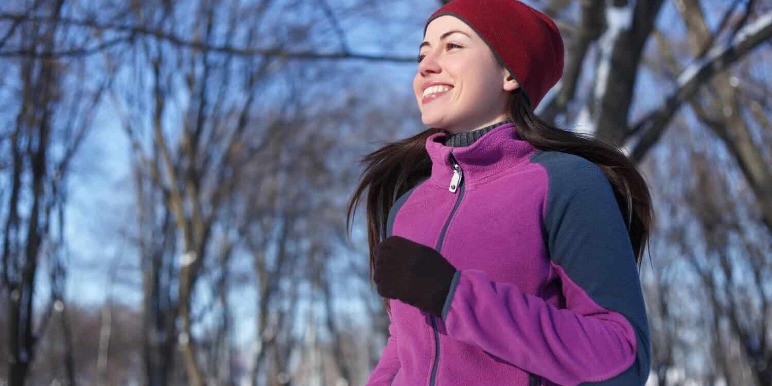 Woman in purple cardigan and red hat exercising outdoors for a positive mindset.