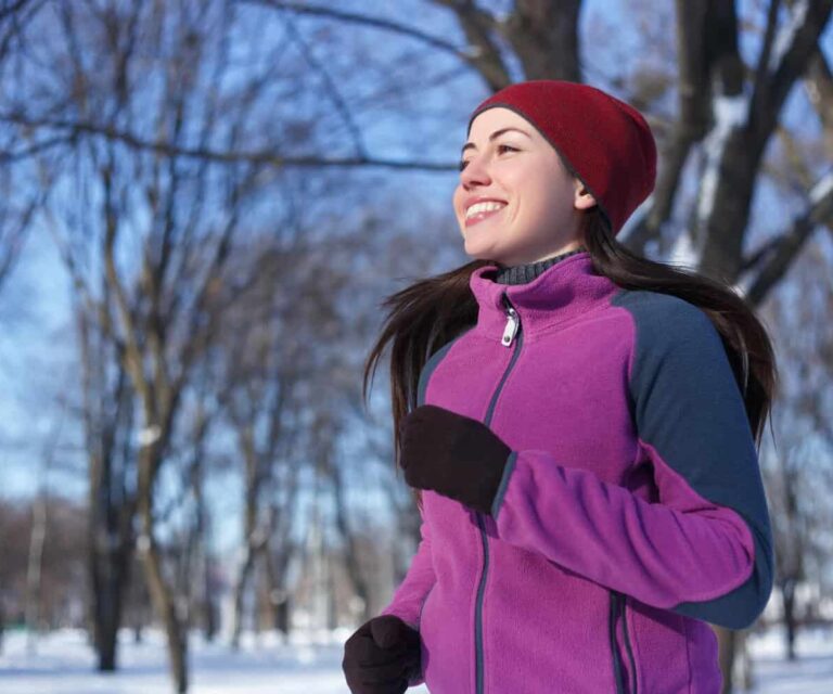 Vrouw in paars vest en rode muts sport buiten voor een positieve mindset.
