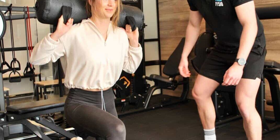 fysiotherapeut helpt een vrouw in grijze sportlegging met niet te hard starten met sporten.