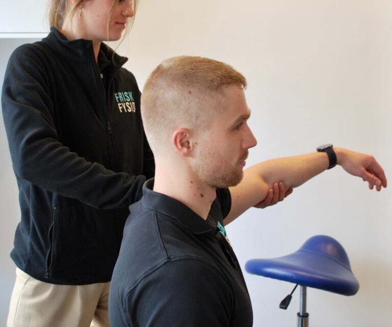 Vrouwelijke fysiotherapeut helpt een man in zwart shirt met oefeningen tegen een peesontsteking in de schouder.