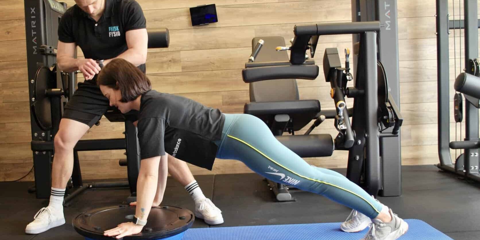 Fysiotherapie oefening met trainer en cliënt Fysiotherapie helpt vrouw met bewegen om blessures in de sportschool te voorkomen.