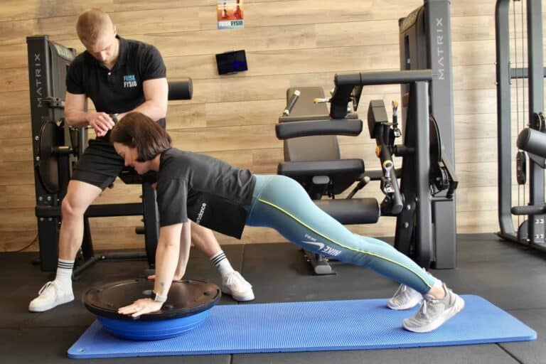 Fysiotherapie oefening met trainer en cliënt Fysiotherapie helpt vrouw met bewegen om blessures in de sportschool te voorkomen.