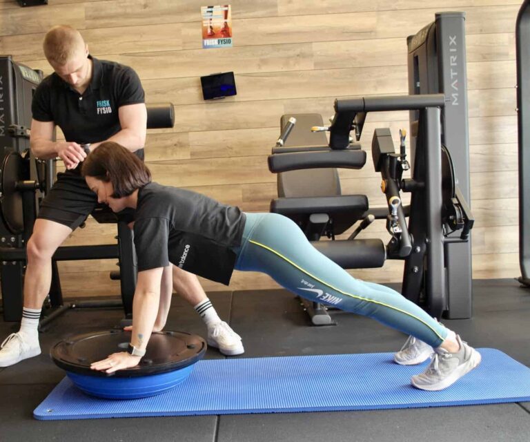 Fysiotherapie oefening met trainer en cliënt Fysiotherapie helpt vrouw met bewegen om blessures in de sportschool te voorkomen.