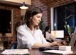 Woman sits at her laptop with a stressed face due to burnout symptoms.