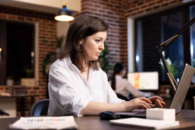 Werkstress en burn-out herstel Vrouw zit achter haar laptop met een gestresst gezicht door klachten bij een burn-out.