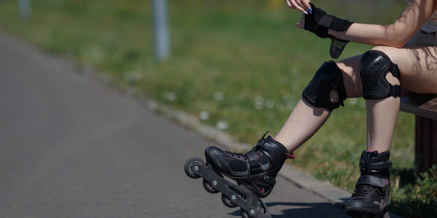 Skateboarder met beschermkleding op straat Meisje zit op een bankje vanwege haar blessures door het skeeleren