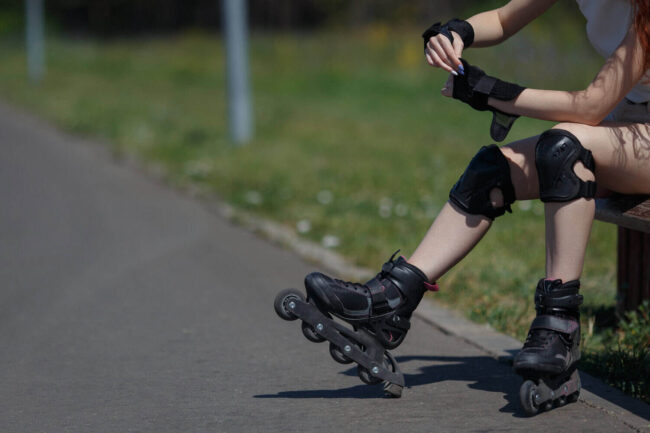 Skateboarder met beschermkleding op straat Meisje zit op een bankje vanwege haar blessures door het skeeleren