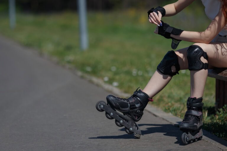 Skateboarder met beschermkleding op straat Meisje zit op een bankje vanwege haar blessures door het skeeleren