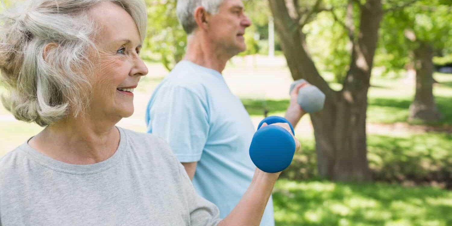Oudere mensen trainen in park Twee oude mensen bewegen buiten om actief te blijven met parkinson.