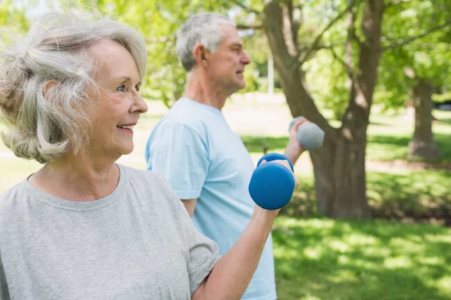 Oudere mensen trainen in park Twee oude mensen bewegen buiten om actief te blijven met parkinson.