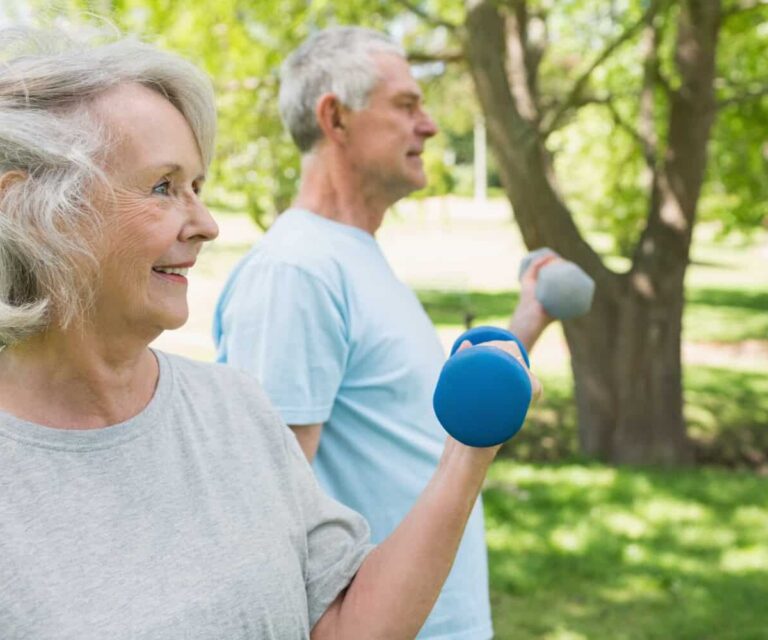 Oudere mensen trainen in park Twee oude mensen bewegen buiten om actief te blijven met parkinson.