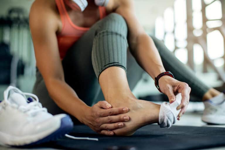 Achilles tendon problems after exercise A woman is sitting with her foot raised because she is suffering from Achilles tendon problems after exercising.