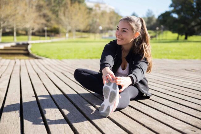 Vrouw stretcht in park na knieblessure Vrouw rekt zich uit tegen een voorste kruisband gescheurd.