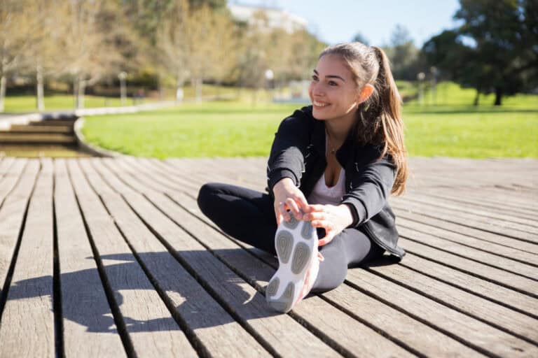 Vrouw stretcht in park na knieblessure Vrouw rekt zich uit tegen een voorste kruisband gescheurd.