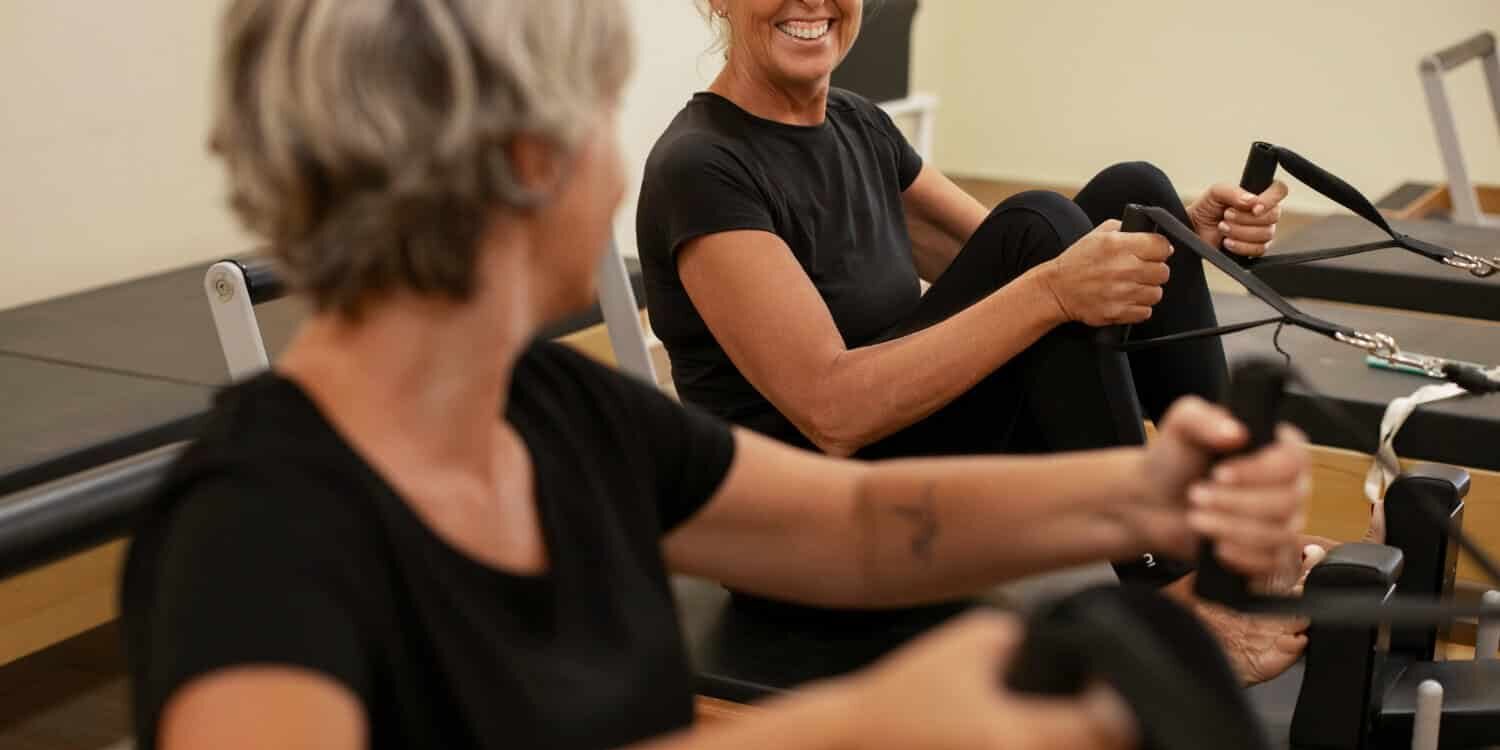 spierkracht behouden na je 60e Twee oudere vrouwen doen sporten voor om te laten zien hoe je spierkracht behouden na je 60e