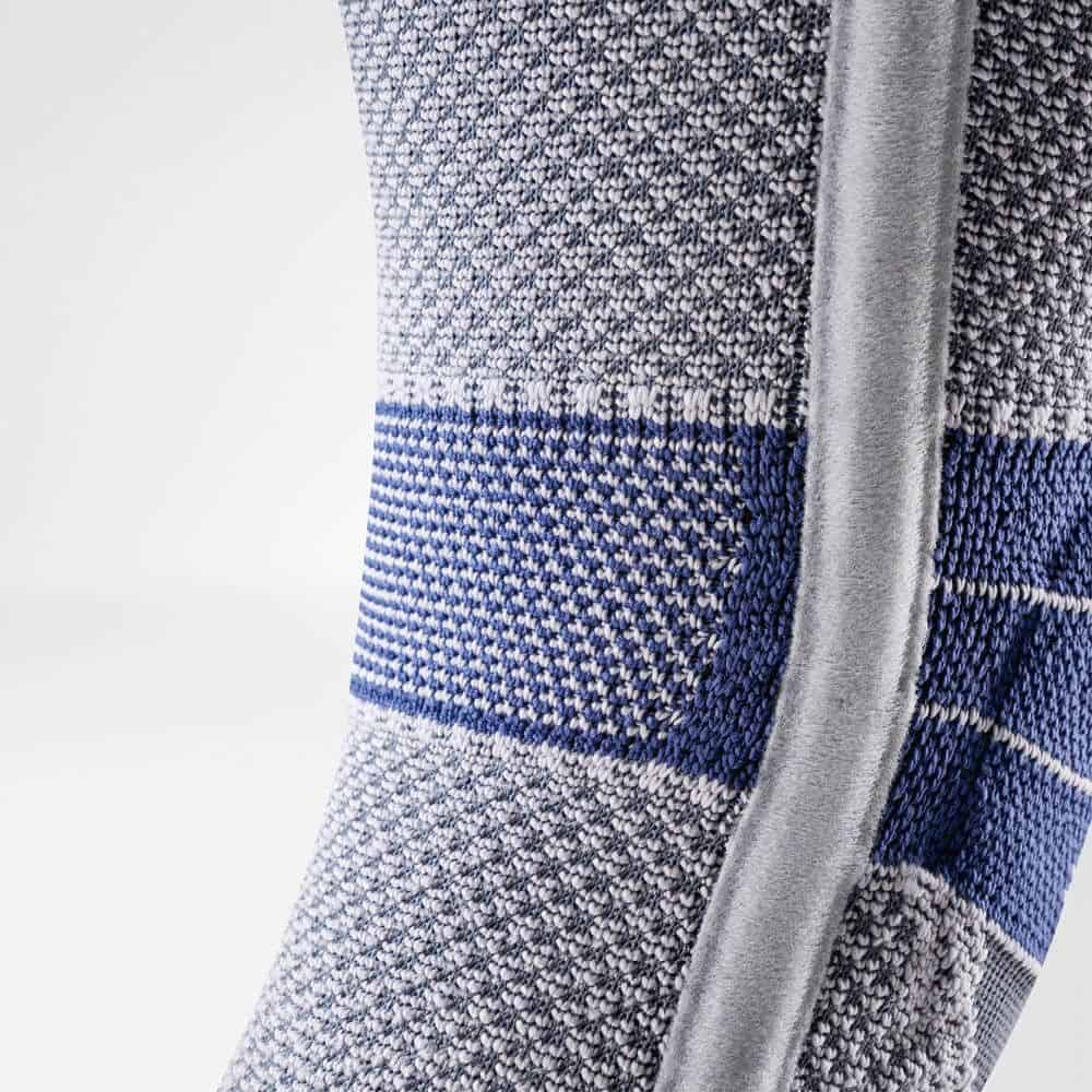 GenuTrain P3 kniebrace 9 Kniebandage close-up van een GenuTrain P3 kniebrace: rood-blauwe gebreide stof met grijze band en naden.