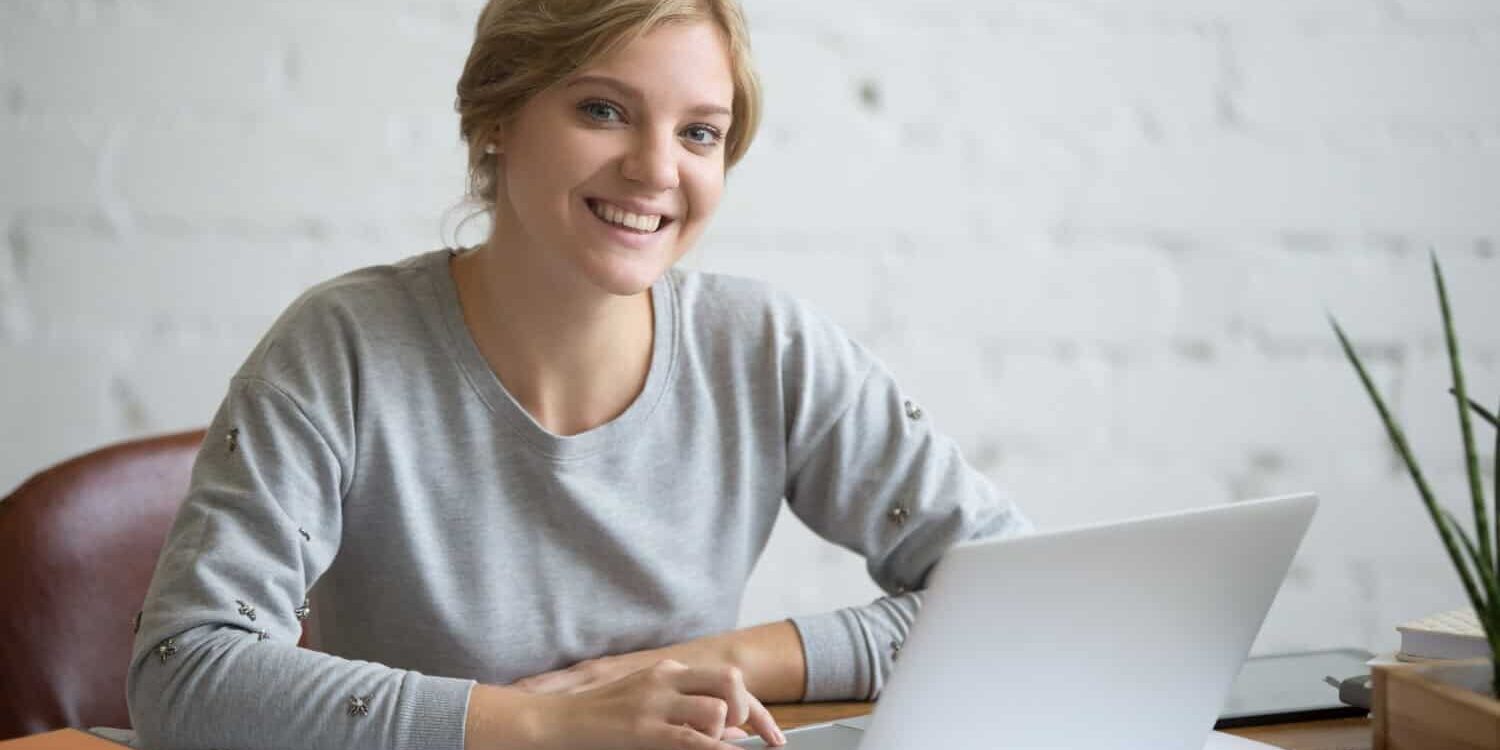 Vrouw zit achter haar laptop en moet uitkijken voor klachten door beeldschermwerk.