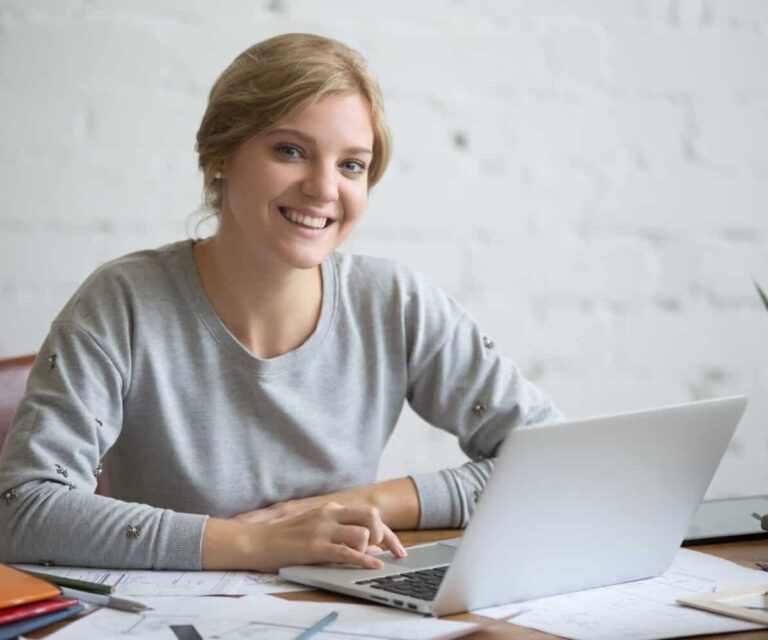 Vrouw zit achter haar laptop en moet uitkijken voor klachten door beeldschermwerk.