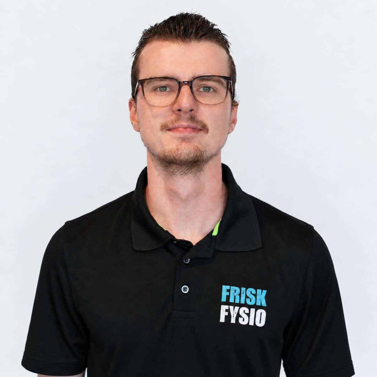 Frisk Fysio staff member in a black polo shirt with a logo, smiling and friendly, professional appearance, healthy lifestyle, physiotherapy practice.