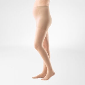 Klant draagt huidkleurige lichaamsondersteunende panty/knie-tot-dijcompressie panty, rechtstaande zijaanzicht.