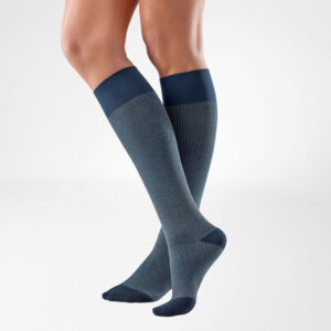 Mannelijke benen dragen lange grijs-blauwe compressiesokken voor ondersteuning en sportcomfort.