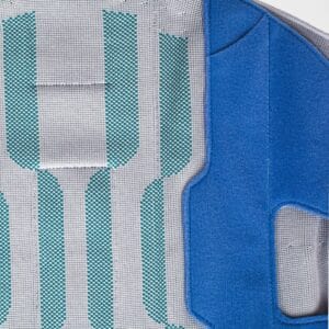 Close-up van een reflecterende veiligheidsvest met turquoise accenten en blauw panel aan de zijkant, ontworpen voor sport- en fysiotherapiedoeleinden bij FRISKFYSIO.