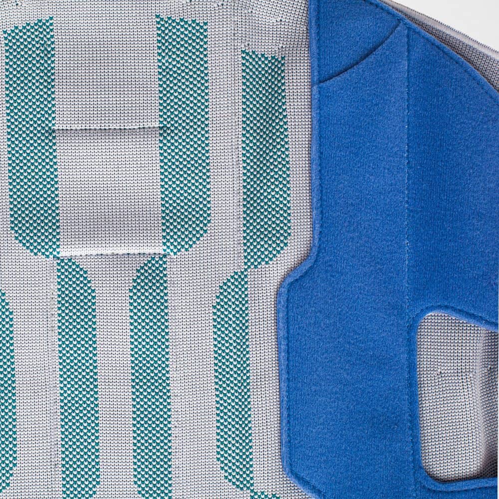 SecuTec® Dorso 2 Close-up van een reflecterende veiligheidsvest met turquoise accenten en blauw panel aan de zijkant, ontworpen voor sport- en fysiotherapiedoeleinden bij FRISKFYSIO.