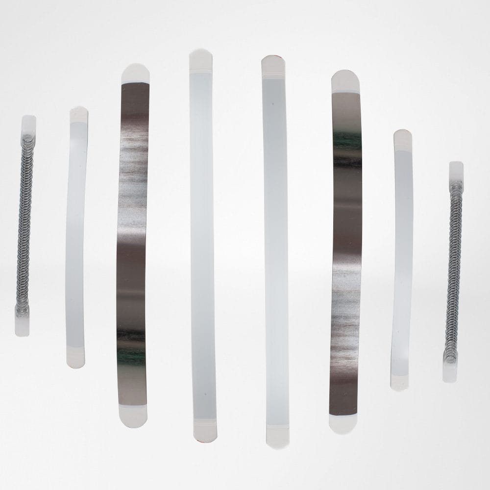 SecuTec® Dorso 3 Abstract wall-mounted reflective strips in varying neutral tones create a modern art composition, with a clean white background.