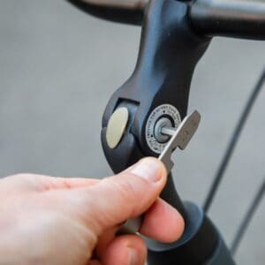 Bicycle parts being adjusted: a close-up of a hand using a metric spanner and wrench on a bike stem or handlebar clamp for maintenance.