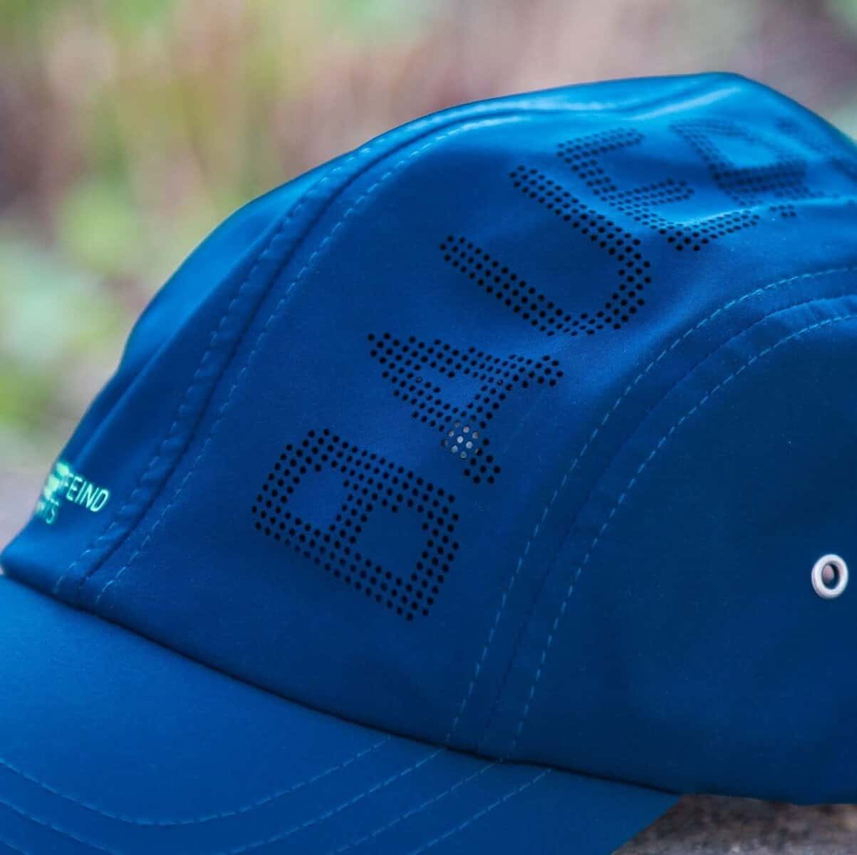 Sports Cap 4 Blauwe baseballpet met letters gespeld op de zijkant, close-up van een sportpet gericht op ergonomie en beweging.
