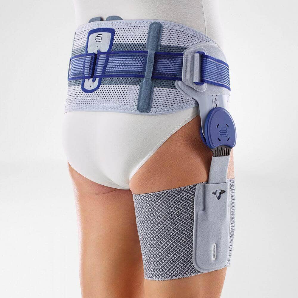 CoxaTrain® 3 Frisbevestiging en knie-/dijbrace voor ondersteuning bij knieletsel, getoond op een model met witte shorts en kousen, in een klinische setting.