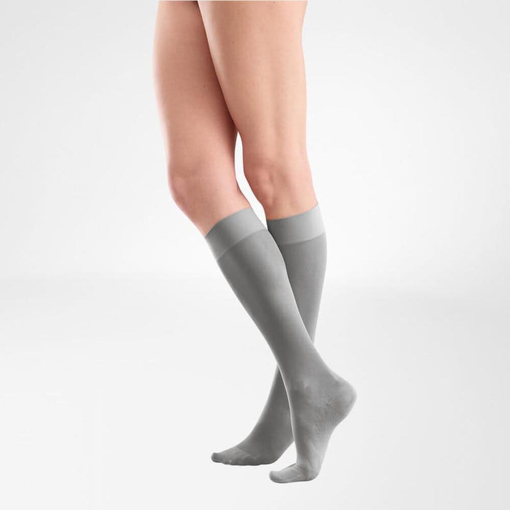 VenoTrain® act SHEER ELEGANCE AD 4 Damesbenen met grijze compressiekousen, staand in een neutrale studio.