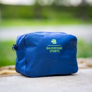 Blue toiletry bag with green Bauerfeind Sports branding on a sandy-coloured border, ready for your sports accessories.