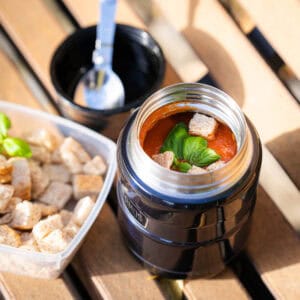 Frisciosie Italian tomato sauce served in a modern kitchen appliance, with croutons on the side and fresh basil as a garnish.