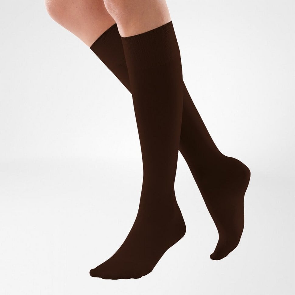 VenoTrain® micro 1 Man/vrouw draagt donkerbruine kniehoogten socksbovenbeenkousen als onderdeel van fysiotherapie of sportcomfort.