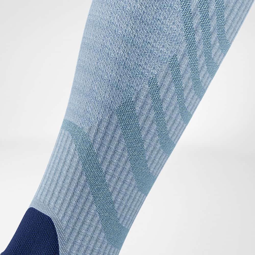 Outdoor Merino Compression Socks 8 A technical-looking sports sock with a knee section featuring a geometric pattern in various shades of blue.