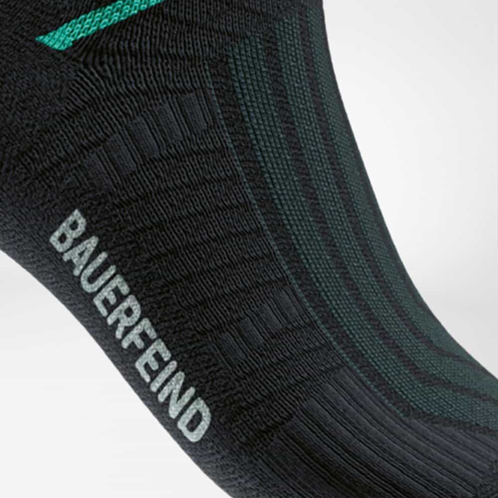 Run Performance Mid Cut Socks 9 Compressiekousen met merklabel Bauerfeind op donkere achtergrond, gericht op ondersteuning en comfort voor sport- en houdingsgezondheid.