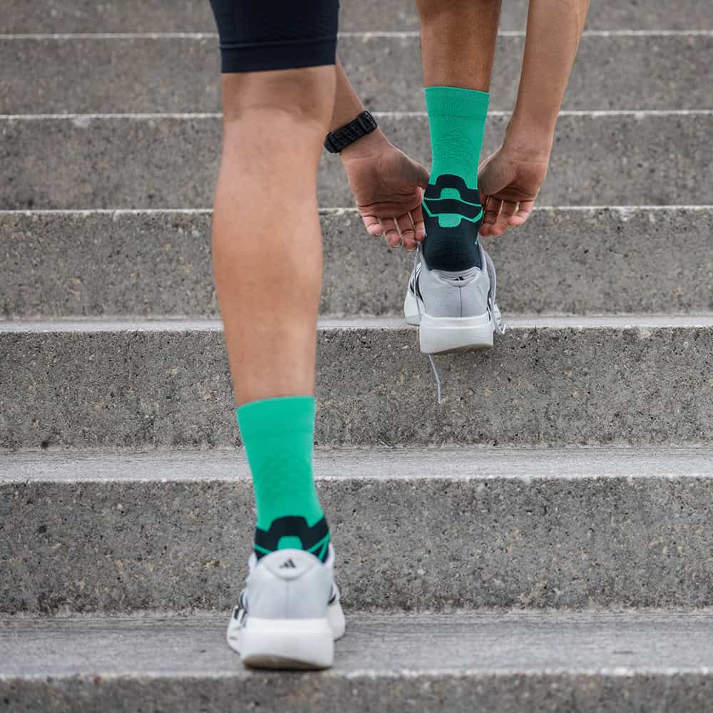 Run Performance Mid Cut Socks 5 Persoon zet stappen op trappen, sportieve groengele voetbalsemgrip enkelsokken en witte hardloopschoenen.