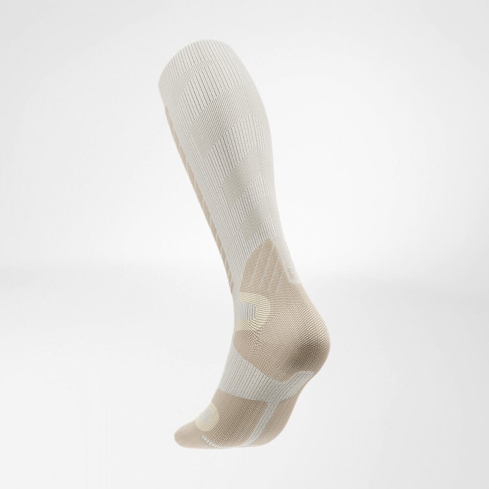 Ski Alpine Compression Socks 3 An anatomically shaped compression knee-to-toe sock in beige and off-white tones, stretchy knit fabric with reinforced heel and toe for support.