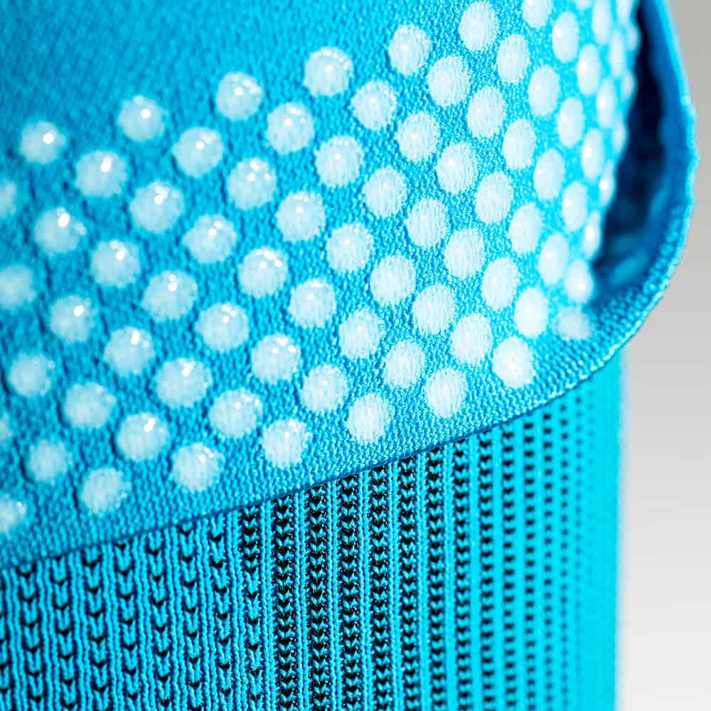 Sports Compression Sleeves Upper Leg 2 Frisk Fysio outdoor sportkleding en gripzone textuur close-up van een blauwe sporttas of -kleding met stippenpatroon en ribbels.