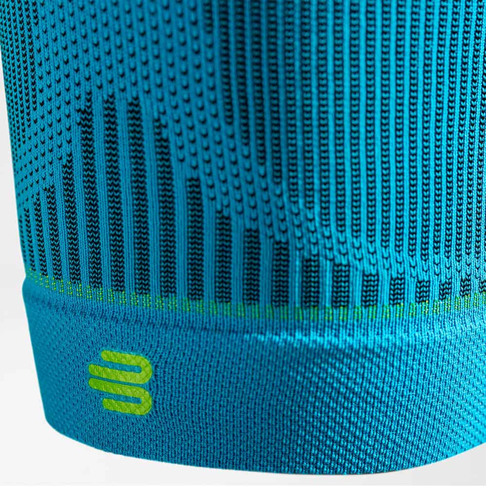 Sports Compression Sleeves Upper Leg 4 Dicht gebreide, blauwe sportmuts met neon groene details en merklogo aan de onderkant, close-up van textielpatroon en ribboord.