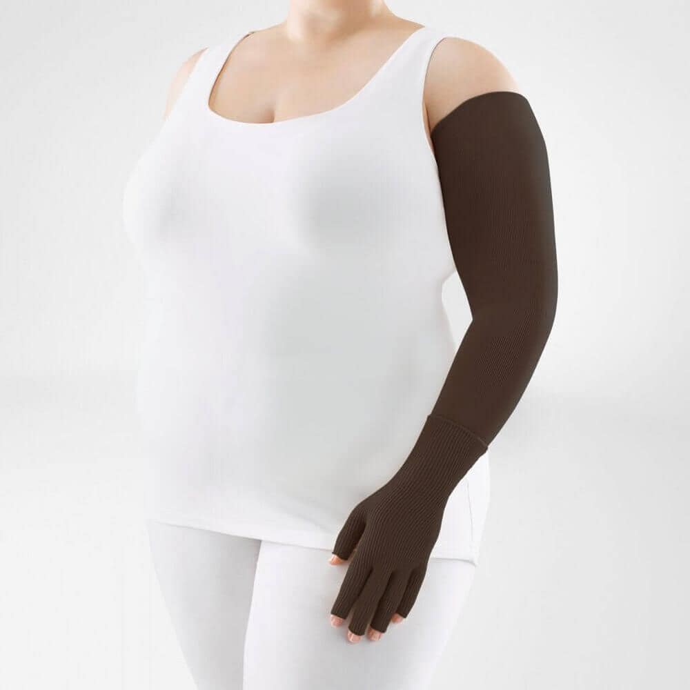 VenoTrain® curaflow armkousen 18 Video/arm protector brace gedragen op een vrouw in wit top en witte broek, korte mouwloze mouwmeter met een brandingloze look; recht voor zich staand, arm in bruin compressiebeenklep, enkel en pols gl.